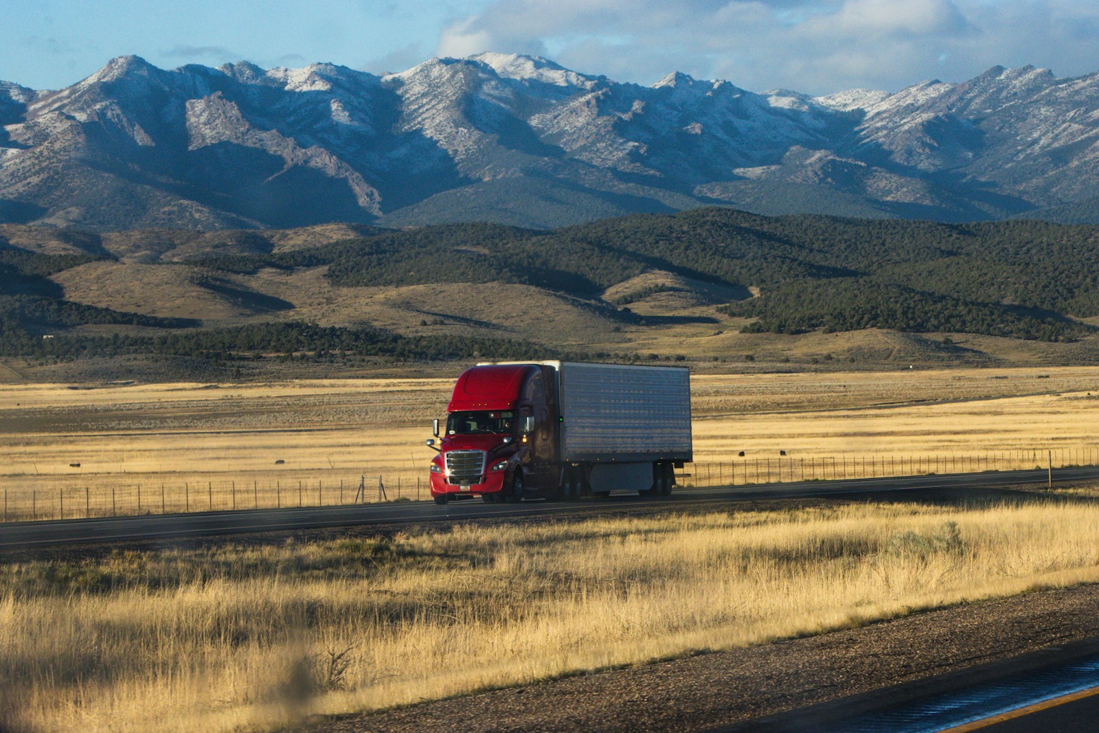 commercial trucking A red semi truck driving down a rural road